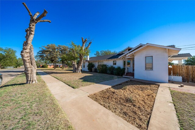 602 E Beauregard St, Rotan, TX 79546 - view of front facade with stucco siding, a front lawn, and fence