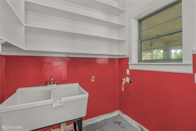 clothes washing area with baseboards and a sink