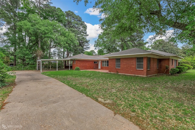 view of property exterior featuring a lawn, brick siding, a carport, and concrete driveway