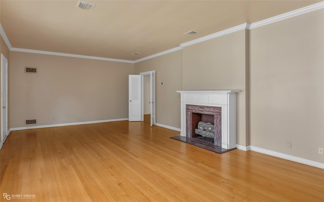unfurnished living room with a high end fireplace, visible vents, light wood finished floors, and crown molding