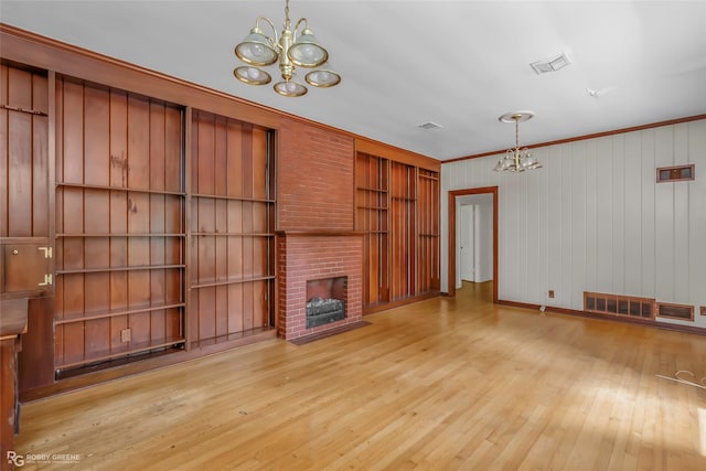 unfurnished living room featuring visible vents, light wood-style floors, and a notable chandelier