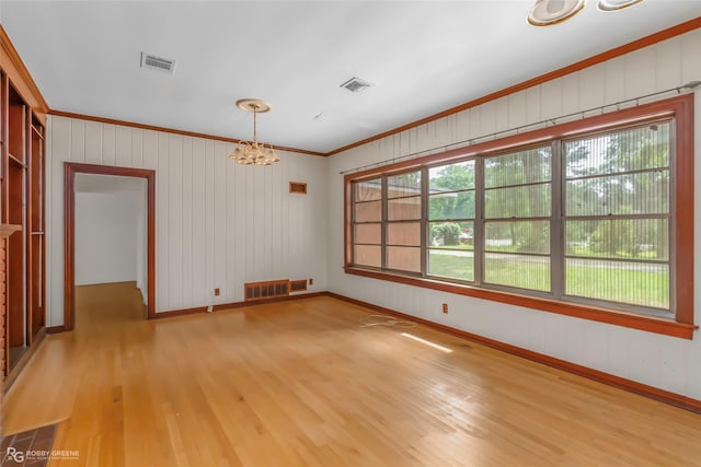 unfurnished room with ornamental molding, a notable chandelier, wood finished floors, and visible vents
