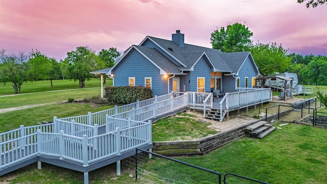 back of property with a wooden deck, fence, and a yard