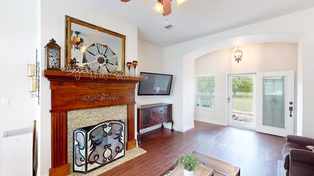 living area featuring arched walkways, wood finished floors, visible vents, and ceiling fan