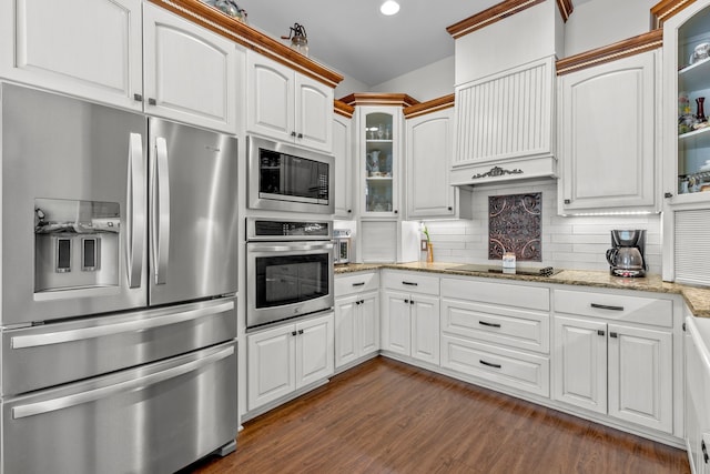 kitchen with tasteful backsplash, glass insert cabinets, light stone countertops, and appliances with stainless steel finishes