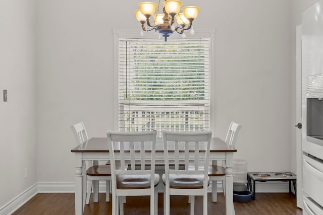 dining area with wood finished floors, baseboards, and a notable chandelier