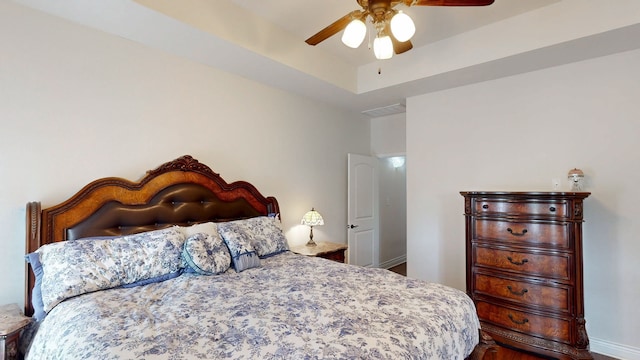 bedroom featuring a tray ceiling, visible vents, and ceiling fan