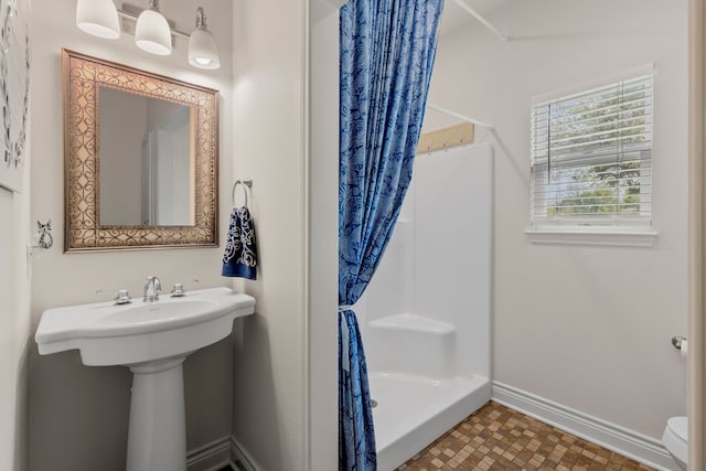 bathroom with baseboards, toilet, and a stall shower
