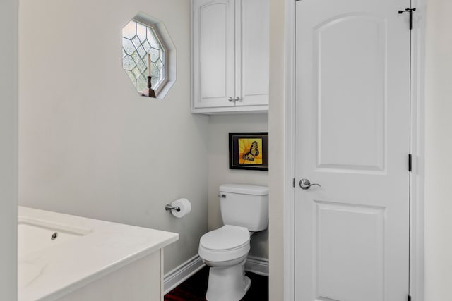 bathroom with baseboards, vanity, and toilet