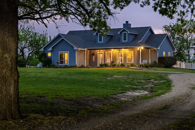 cape cod home with a chimney, driveway, fence, a porch, and a front yard