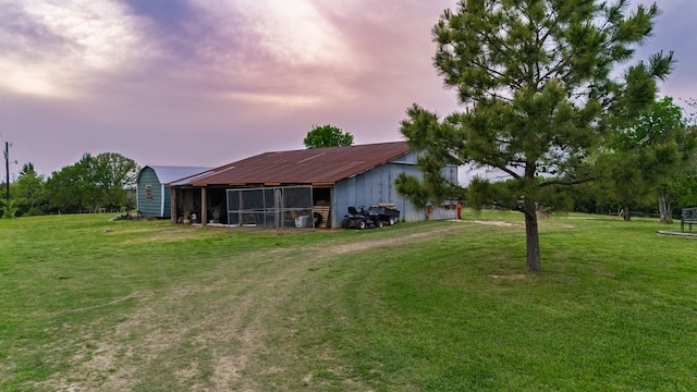 back of property at dusk with an outbuilding and a yard