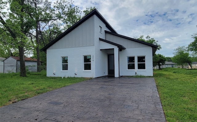 view of front facade featuring a front lawn, board and batten siding, and brick siding