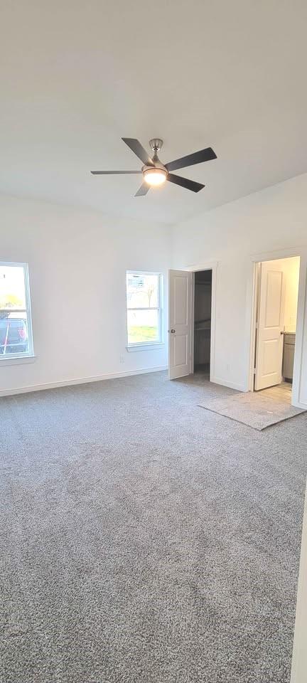 unfurnished bedroom with baseboards, ceiling fan, light carpet, and a closet