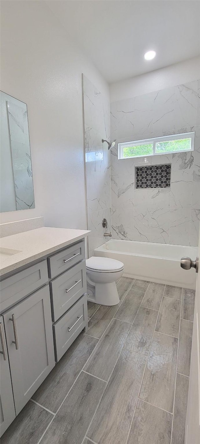 bathroom with wood tiled floor, shower / washtub combination, toilet, and vanity