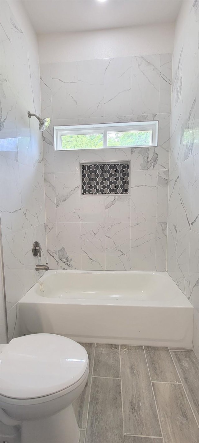 bathroom with toilet, shower / tub combination, wood finished floors, and a healthy amount of sunlight