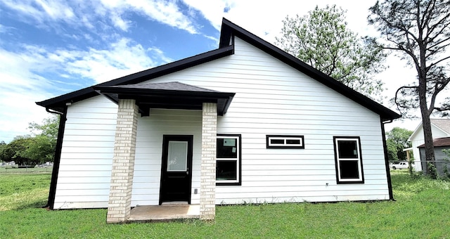 rear view of property featuring a lawn