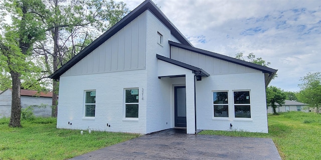 view of front of property featuring brick siding, board and batten siding, and a front lawn