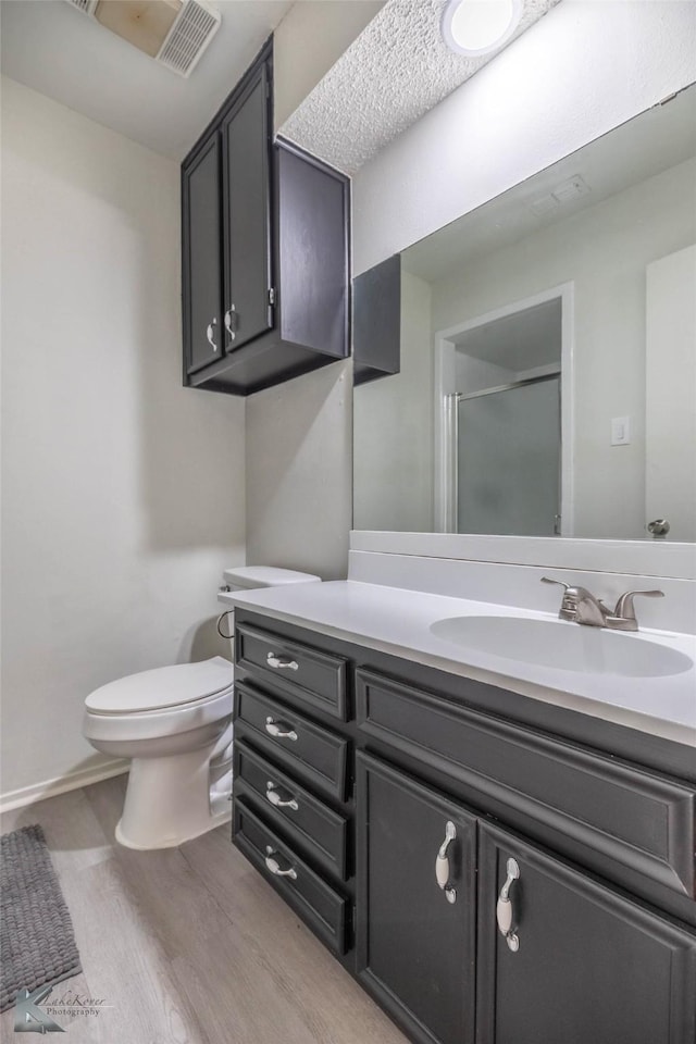 1026 Baylor St, Abilene, TX 79602 - full bath with toilet, wood finished floors, vanity, visible vents, and a stall shower