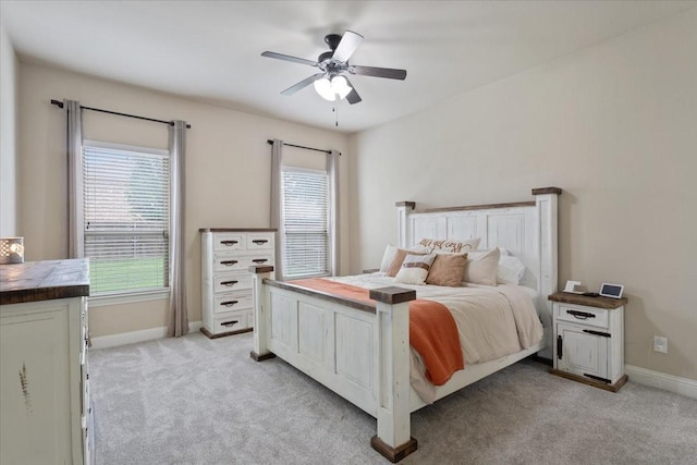 bedroom featuring light colored carpet, baseboards, and ceiling fan