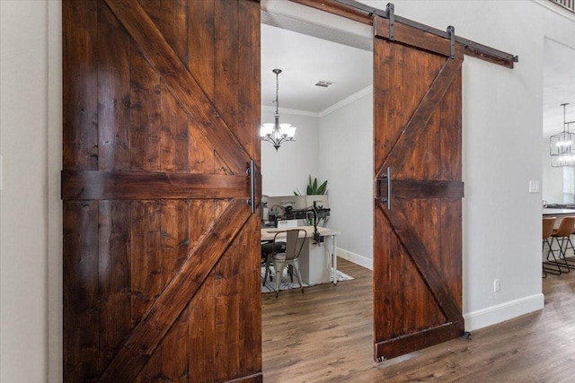 corridor with baseboards, ornamental molding, a barn door, and wood finished floors