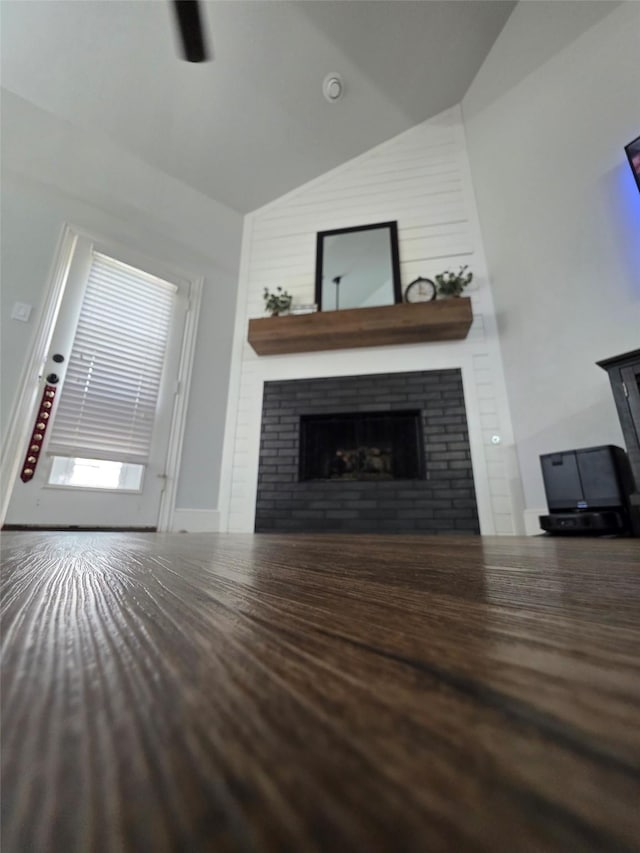 unfurnished living room with wood finished floors, high vaulted ceiling, and a large fireplace