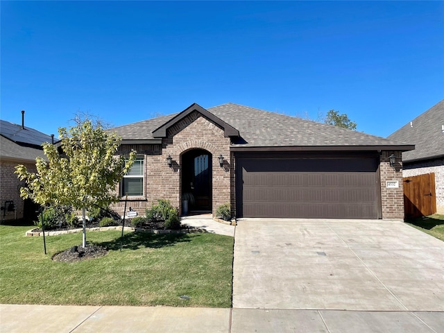 ranch-style home with concrete driveway, brick siding, an attached garage, a shingled roof, and a front yard
