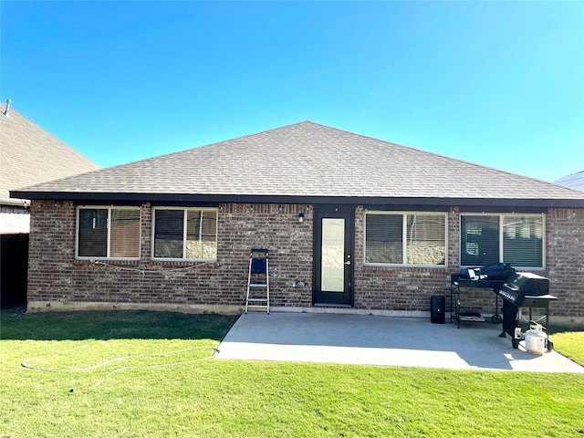 back of property featuring brick siding, a yard, a patio, and a shingled roof
