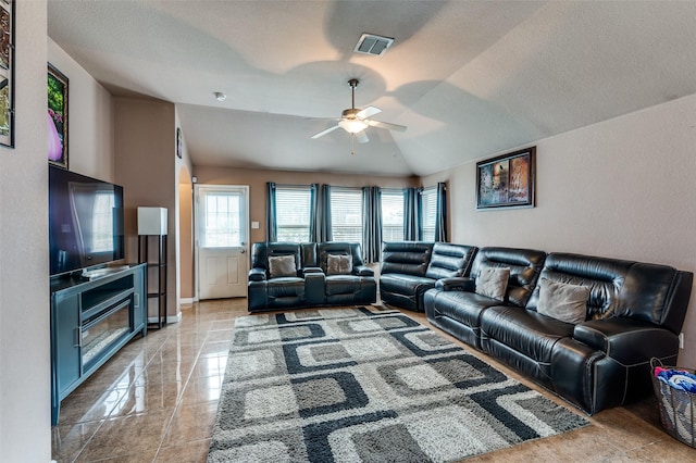 living room with lofted ceiling, visible vents, a ceiling fan, baseboards, and a textured ceiling