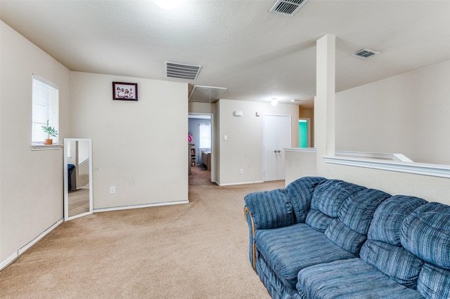 carpeted living area with attic access, baseboards, and visible vents