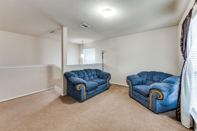 carpeted living area featuring baseboards, visible vents, and a textured ceiling
