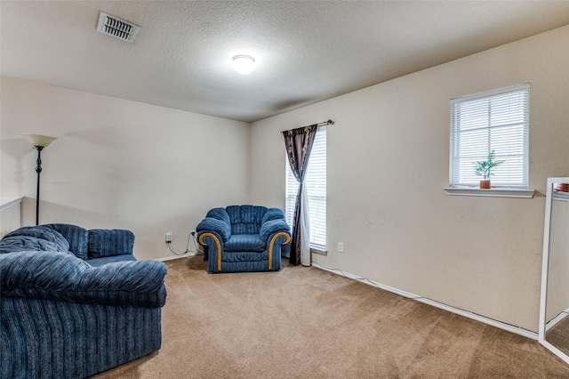living area featuring baseboards, visible vents, and carpet