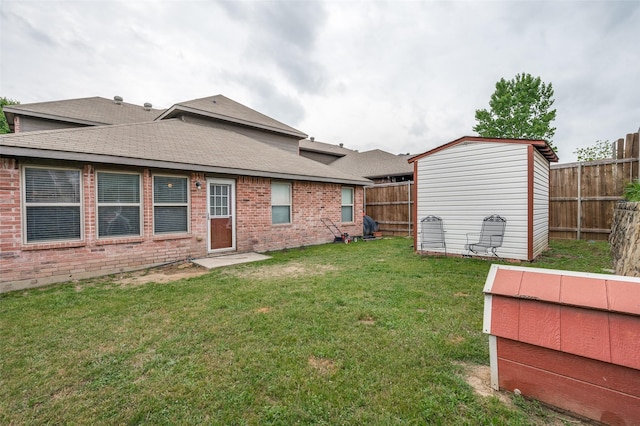 back of property with a fenced backyard, a yard, an outdoor structure, a storage unit, and brick siding