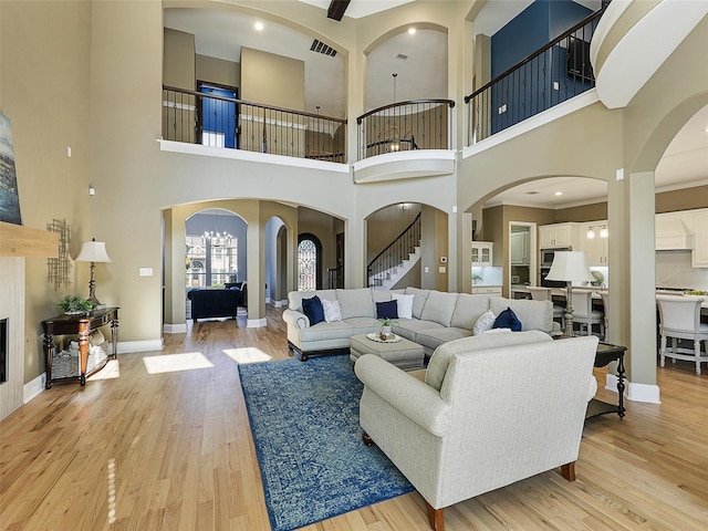 living room featuring light wood-type flooring, baseboards, arched walkways, and stairway
