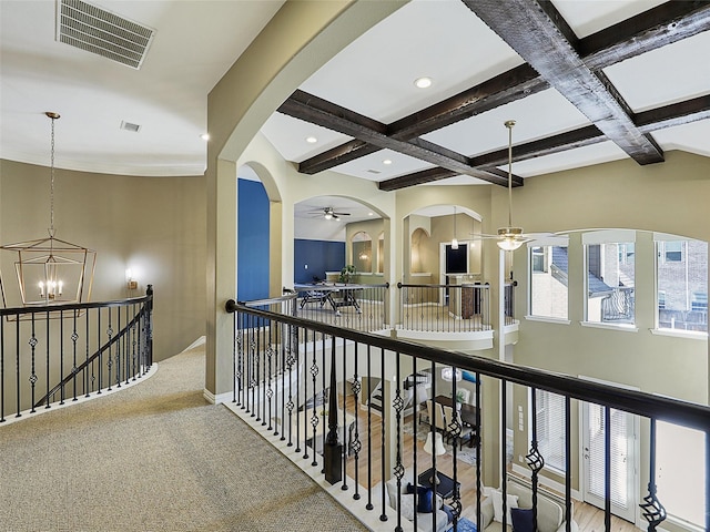 hallway featuring an inviting chandelier, coffered ceiling, visible vents, an upstairs landing, and beamed ceiling