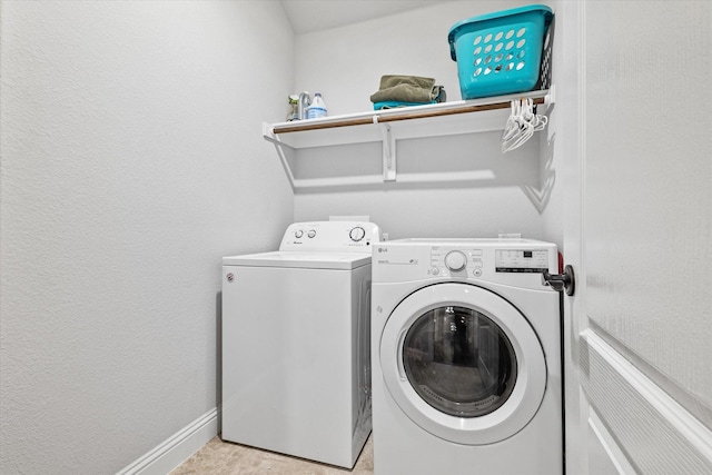 laundry area with baseboards, a textured wall, washer and clothes dryer, and laundry area