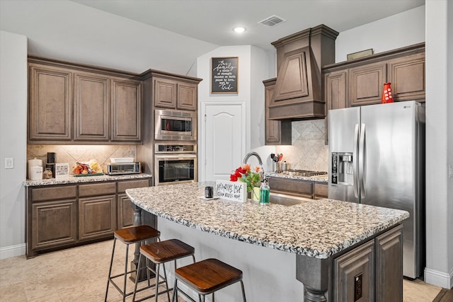 kitchen with stainless steel appliances, a sink, visible vents, baseboards, and custom exhaust hood