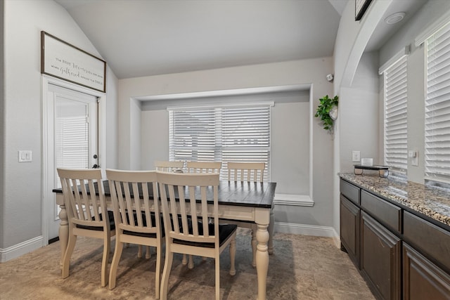 dining room featuring baseboards, vaulted ceiling, and plenty of natural light