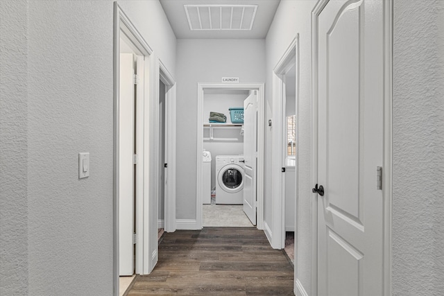 corridor with washing machine and dryer, a textured wall, visible vents, and dark wood finished floors