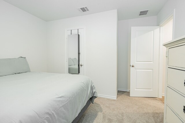 bedroom with baseboards, visible vents, and light colored carpet