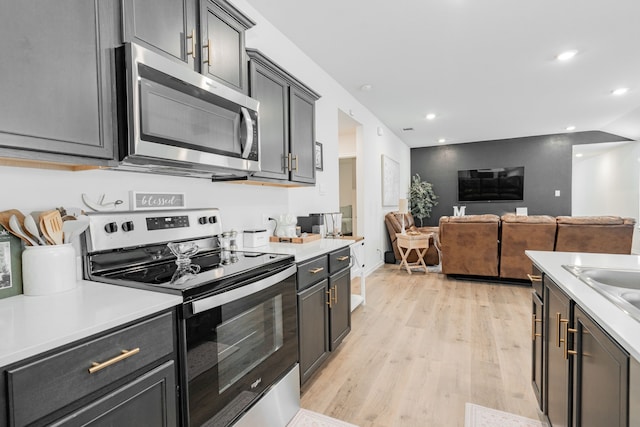 kitchen with recessed lighting, light countertops, light wood-style floors, appliances with stainless steel finishes, and open floor plan