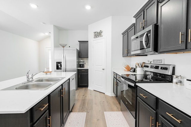kitchen with recessed lighting, light wood finished floors, stainless steel appliances, light countertops, and a sink