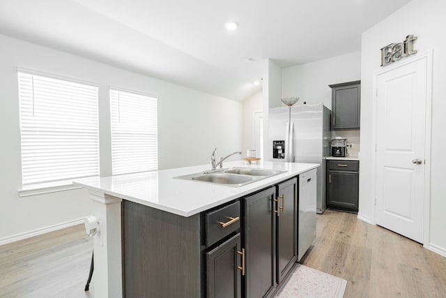 kitchen featuring light countertops, light wood-style flooring, a kitchen island with sink, and a sink