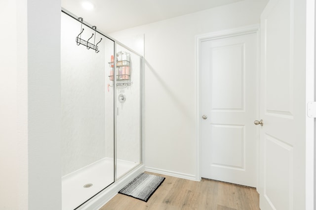bathroom featuring baseboards, wood finished floors, and a stall shower