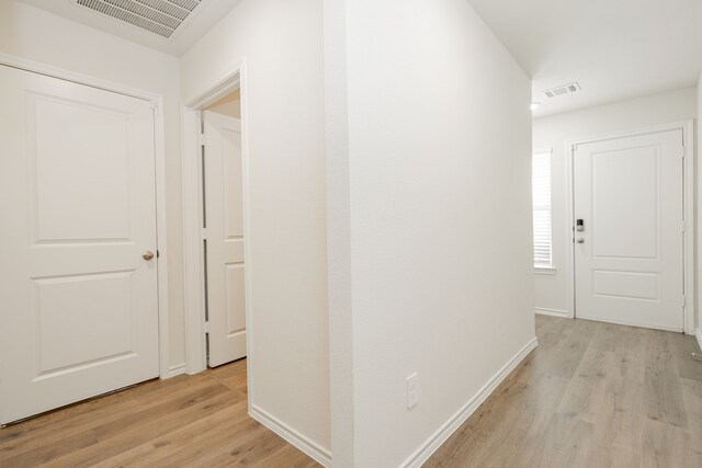 corridor featuring light wood-type flooring, visible vents, and baseboards