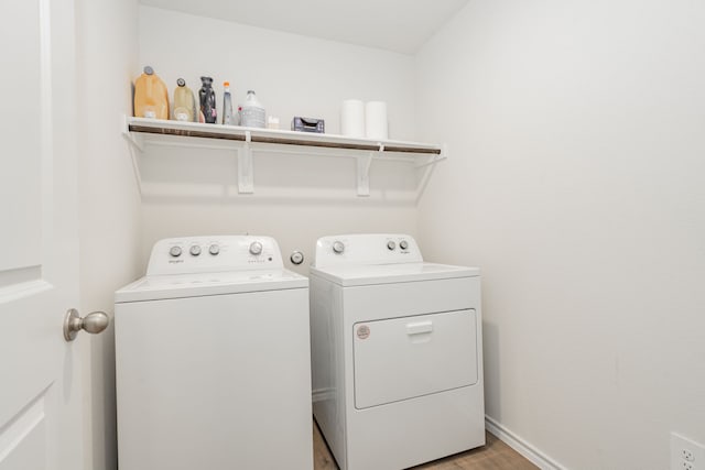 clothes washing area featuring baseboards, washer and clothes dryer, laundry area, and light wood-style floors