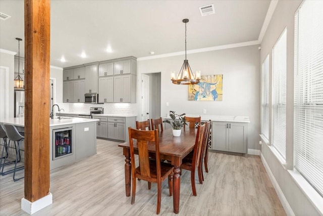 12409 Messer Ct, Fort Worth, TX 76126 - dining space featuring a chandelier, crown molding, light wood finished floors, beverage cooler, and baseboards