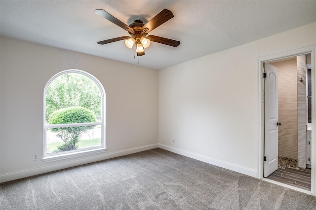 carpeted spare room featuring a ceiling fan and baseboards