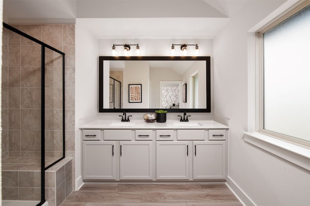 bathroom with a sink, a stall shower, double vanity, and wood finished floors