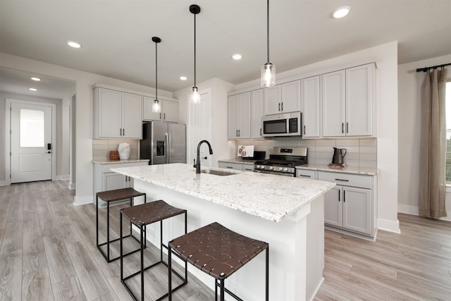kitchen with stainless steel appliances, a kitchen breakfast bar, a center island with sink, tasteful backsplash, and baseboards