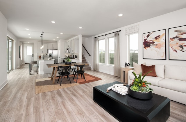 living room featuring recessed lighting, light wood-style flooring, and stairs